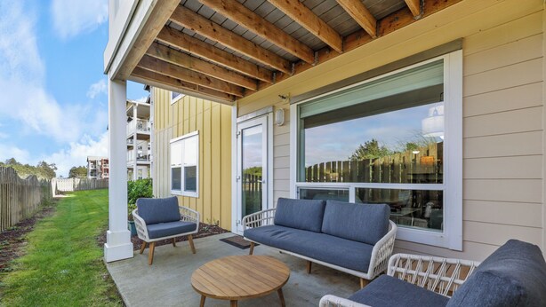 A covered patio with a sofa, chairs, and a round table. - 1013 - Coastal Haven Retreat (Westport)