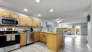 A modern kitchen with wooden cabinets, stainless steel appliances, and a large island. - 1013 - Coastal Haven Retreat (Westport)