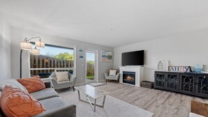 A modern living room with a grey sofa, white coffee table, and a fireplace. - 1013 - Coastal Haven Retreat (Westport)