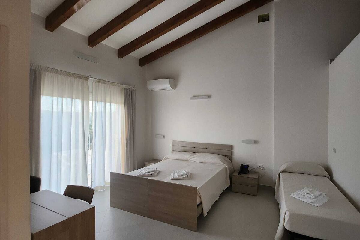 A hotel room with a large bed, a smaller bed, a desk, and a chair.
