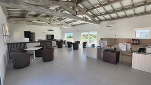 A spacious open-plan living area with a kitchen, seating, and a balcony with a view. - HOTEL BORGO DELL'ORSO (Palau)