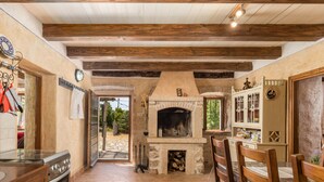 Una cocina rústica con suelo de ladrillo, armarios de madera, horno empotrado y chimenea de piedra.