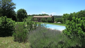 A swimming pool surrounded by lush greenery and a stone building in the background. - Casale Vitello by Interhome (Lago di Bolsena)