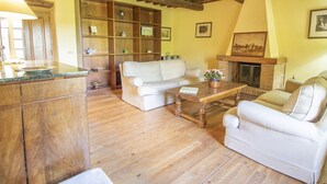 A cozy living room with wooden floors, a fireplace, a sofa, a coffee table, and a wooden cabinet. - Casale Vitello by Interhome (Lago di Bolsena)