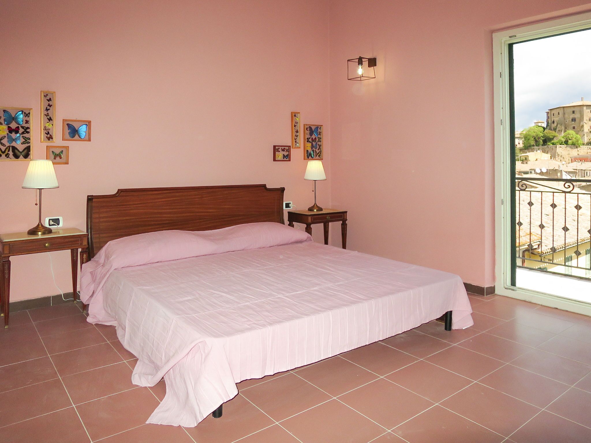 A bedroom with a bed, two bedside tables, a window with a view, and wall art.