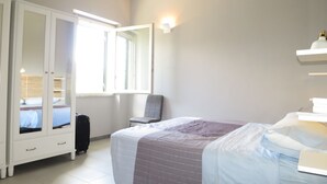 Une chambre à coucher avec un lit, une armoire, une chaise et une fenêtre.