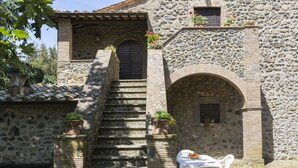 A stone building with a staircase leading to a door, a small table with chairs, and potted plants. - La Capraccia by Interhome (Lago di Bolsena)