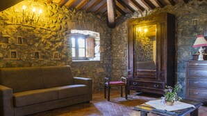 A rustic room with stone walls, a wooden ceiling, a leather sofa, a wooden table with a basket, and a wooden cabinet. - La Capraccia by Interhome (Lago di Bolsena)