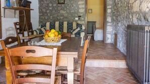A rustic dining area with a stone wall, wooden furniture, and a fruit basket on the table. - La Capraccia (BOL334) by Interhome (Lago di Bolsena)