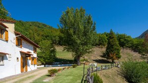 Un edificio bianco con persiane di legno, un prato verde e una recinzione in legno.