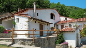 Un edificio in pietra dal tipico aspetto, con tetto in tegole, una recinzione in legno e una scala in pietra che conduce a una porta.