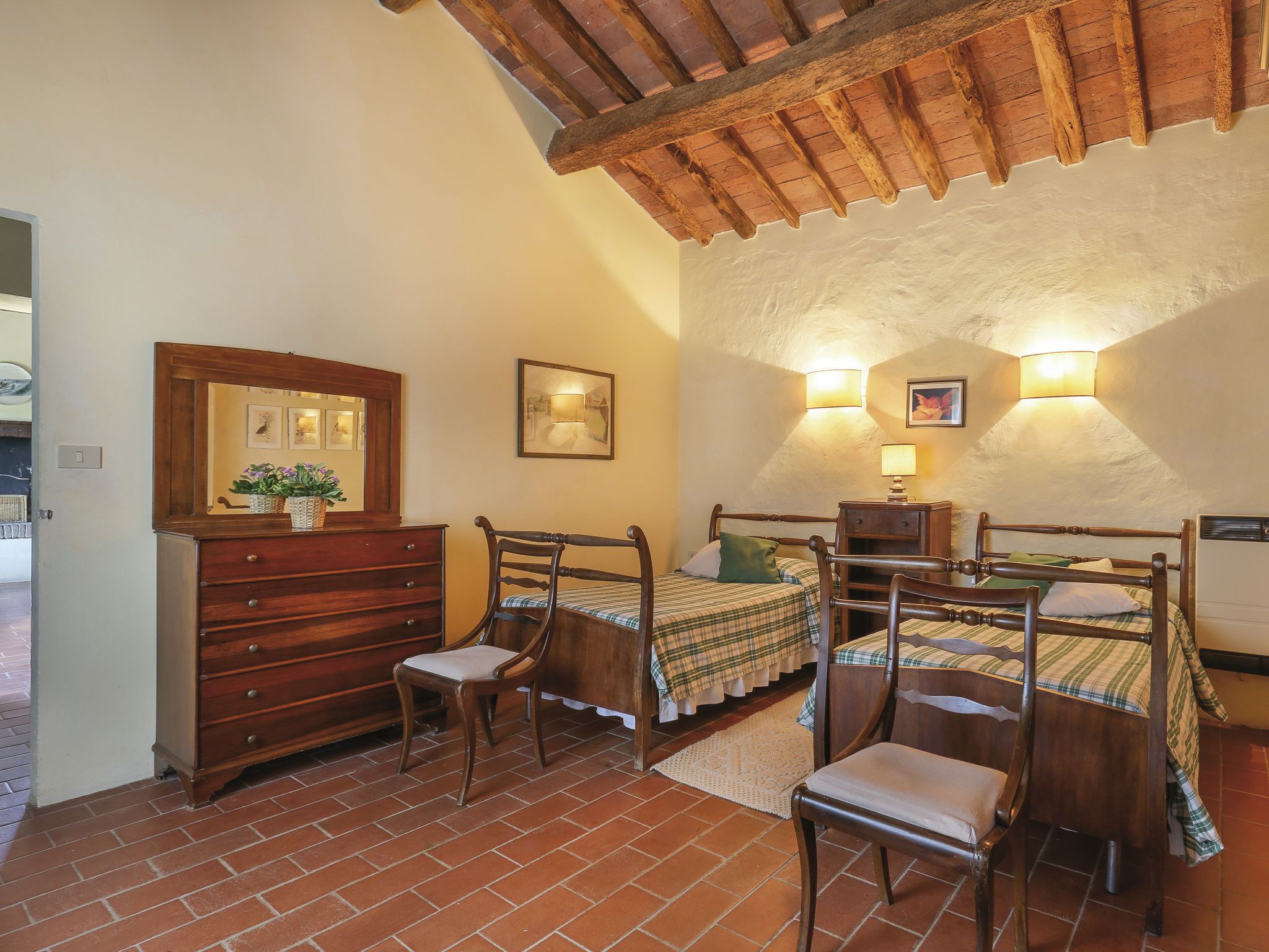 A bedroom with two wooden beds, a dresser, and a chair.