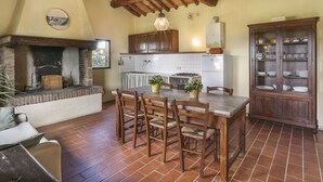A rustic kitchen with exposed wooden beams, a brick fireplace, and a dining area with a table and chairs. - Terra Bianca (PAA136) by Interhome (Palaia)