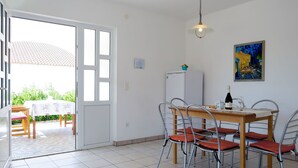 Un comedor con mesa y sillas, una lámpara en el techo, un refrigerador y un cuadro en la pared.