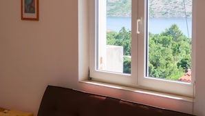 Una stanza con una grande finestra che si affaccia su un lago e delle colline, un divano marrone e un quadro appeso al muro.
