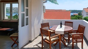 Un patio con un tavolo rotondo, sei sedie di legno e una bottiglia di vino.