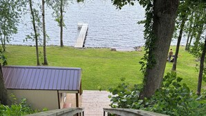 A wooden staircase leading to a dock by a lake, surrounded by trees and greenery.
