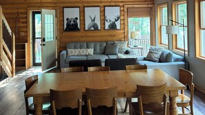 A spacious wooden interior with a dining area, sofa, and ceiling fan.