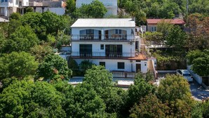 A multi-story building with balconies, surrounded by lush greenery and hills. - Dalibor by Interhome (Senj)