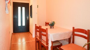 A dining area with a table and chairs, a door with a window, and a wall-mounted picture. - Dalibor by Interhome (Senj)