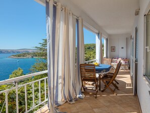 Enjoy breathtaking views of the water and coastline from this balcony, featuring a table and chairs.
