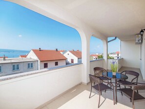 A balcony with wicker chairs and a table, overlooking a coastal town with red-roofed buildings. - Apartment Nikol by Interhome (Crikvenica)