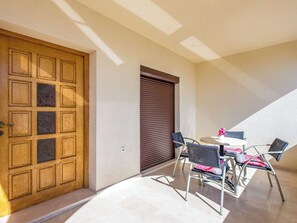 A sunlit patio with a wooden door, a sliding shutter, and outdoor furniture. - Apartment Nikol by Interhome (Crikvenica)