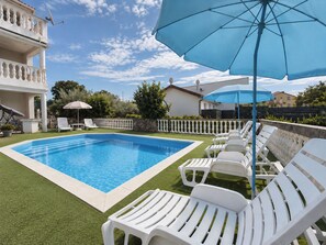 A swimming pool with white lounge chairs and a blue umbrella.