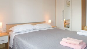 Une chambre d’hôtel avec un lit, des lampes de chevet, une armoire et un tableau encadré au mur.