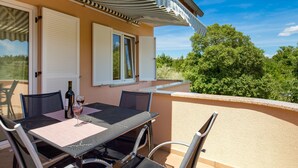 Eine Terrasse mit Tisch und Stühlen, einer Weinflasche und einem Weinglas.