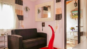 A living room with a sofa, a red chair, a mirror, and a small table with a potted plant. - Apartment Dilly by Interhome (Krk/Pinezići)