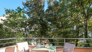 Une terrasse extérieure avec une table dressée pour deux personnes, entourée de chaises en métal et agrémentée d’une rambarde.