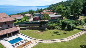 Une villa avec piscine, entourée d’un jardin et offrant une vue sur la mer.