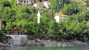 A coastal area with buildings on a hillside, a pier, and a large arrow pointing upwards.