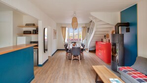 A modern kitchen with a dining area, a red cabinet, and a wooden bench. - 190m from the beach, downtown, house for 8 (Pléneuf-Val-André)