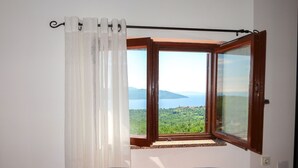 Ein Schlafzimmer mit einem Bett, einem Fenster mit Blick auf eine Landschaft und einem Vorhang.