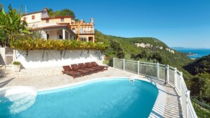 A villa with a swimming pool, a terrace with lounge chairs, and a view of the sea and hills. - Princip by Interhome (Rabac)