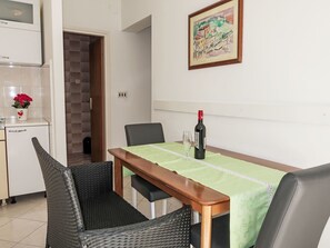 Ein Essbereich mit einem Tisch für zwei Personen, einer Weinflasche und einem Gemälde an der Wand.