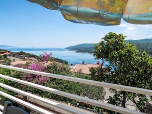 A balcony with a view of a coastal landscape, including houses and a body of water.
