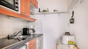 A compact kitchen with a dishwasher, coffee maker, toaster, and a small table with a bowl of fruit. - Seaview - flat for 4 (Pornichet)
