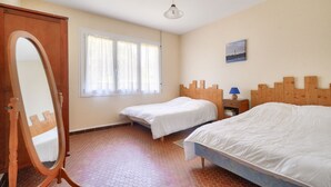 A bedroom with two single beds, a wooden headboard, a bedside table with a lamp, a mirror, and a window with curtains. - Less than 2km from the beach, house for 6 (Andernos-les-Bains)