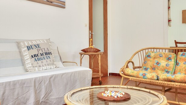 A room with a bed, a wicker sofa, a small table with a basket, and a door with a view of a beach. - Less than 2km from the beach, house for 6 (Andernos-les-Bains)