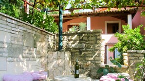 A stone-walled outdoor area with a stone table and two pink cushions. - Vacation home Noel by Interhome (Labin)