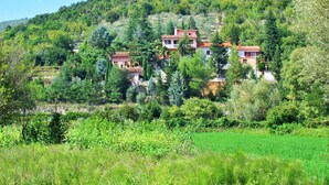 A hillside property with multiple buildings, surrounded by lush greenery and a clear sky. - Vacation home Noel by Interhome (Labin)