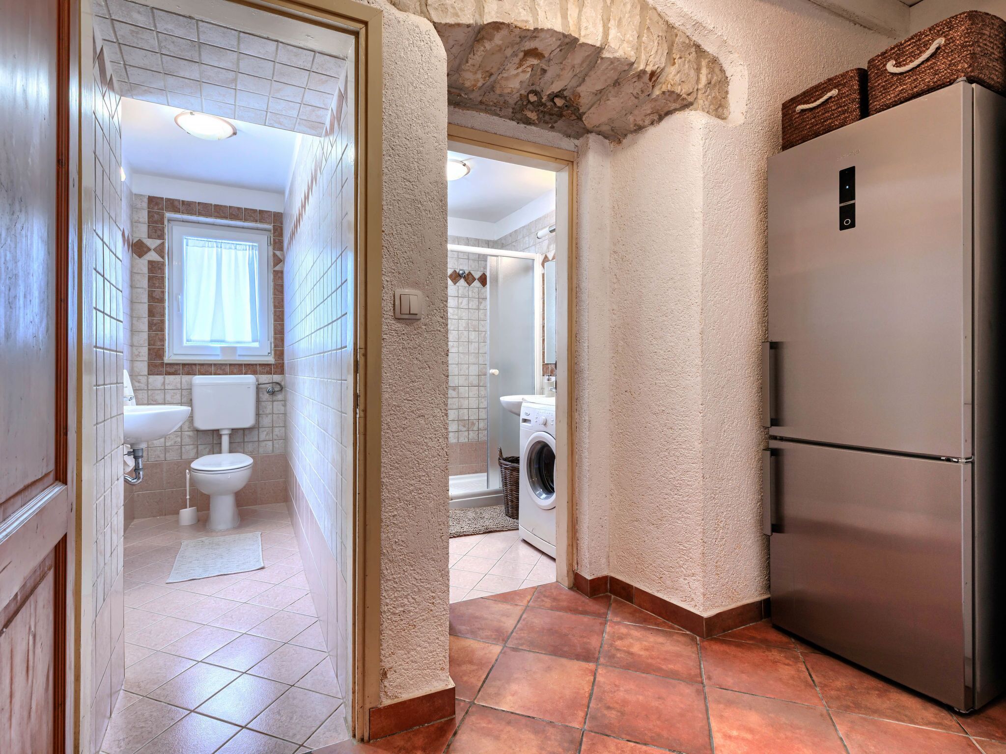 Una cocina moderna con un refrigerador de acero inoxidable, una lavadora y un lavamanos.