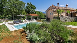 Ein Haus mit Swimmingpool, Sitzgelegenheiten im Freien und einem Garten.