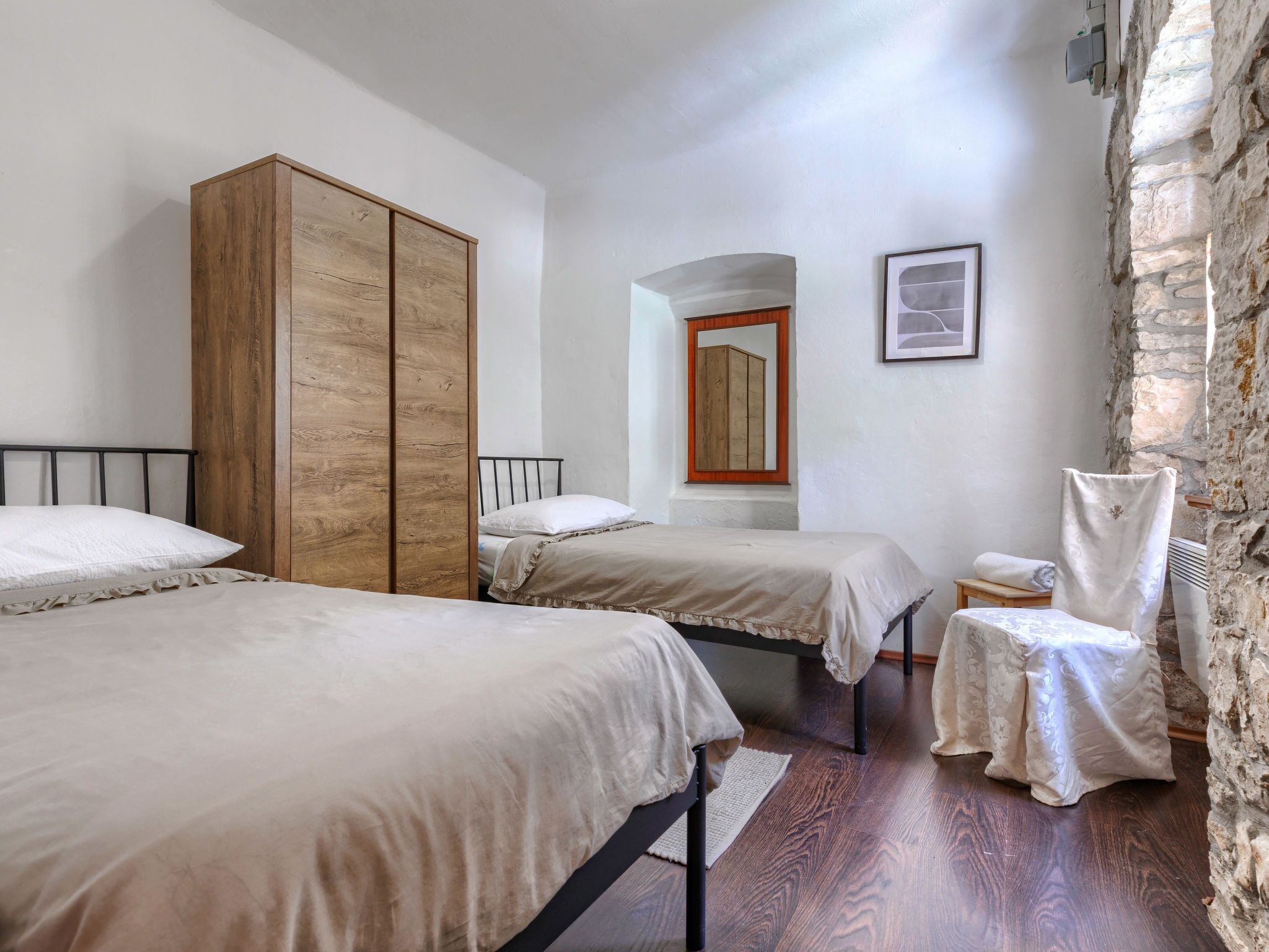Une chambre avec deux lits, une armoire en bois, une petite table et une chaise.