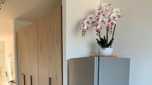 Una cocina moderna con refrigerador de acero inoxidable, armarios de madera y una orquídea en maceta encima.