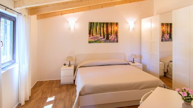 A bedroom with a bed, bedside tables, a window, and a painting on the wall. - Vacation home Sara by Interhome (Poreč)