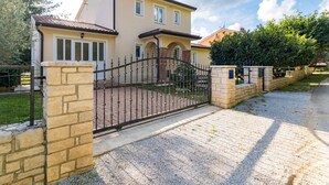 A two-story house with a gated driveway and a stone wall. - Vacation home Lara by Interhome (Poreč)